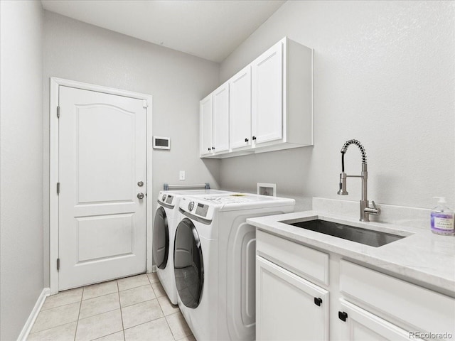 washroom featuring cabinet space, light tile patterned floors, baseboards, washer and clothes dryer, and a sink