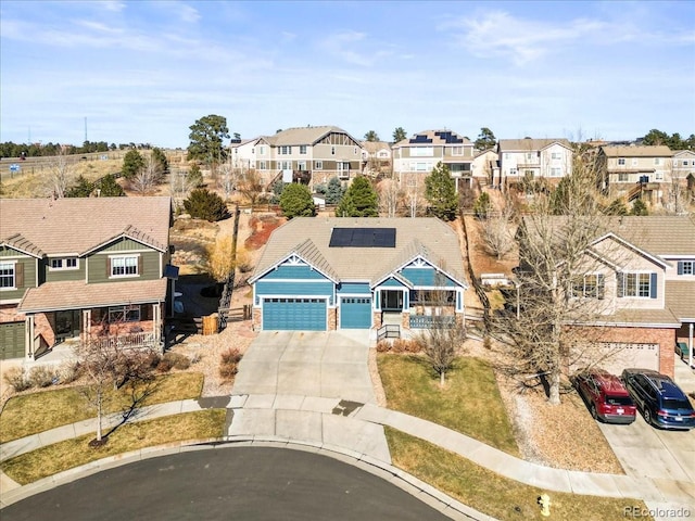 view of front of home featuring a garage, solar panels, a residential view, and concrete driveway