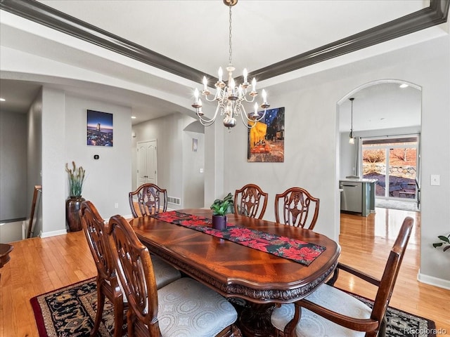 23327 E Ottawa Dr, Aurora, CO 80016 - dining space with arched walkways, hardwood / wood-style floors, ornamental molding, a chandelier, and a tray ceiling
