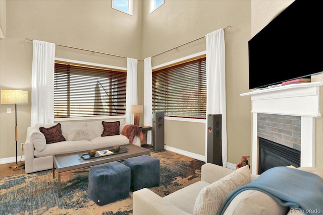 living room with a fireplace, baseboards, and a towering ceiling