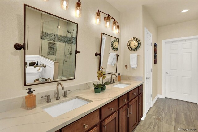 bathroom featuring a sink, a soaking tub, double vanity, and a shower stall