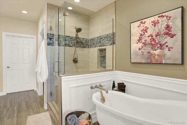 bathroom featuring recessed lighting, wainscoting, a stall shower, and a freestanding bath