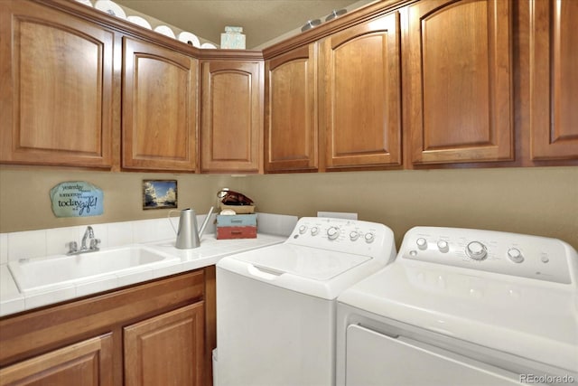 washroom featuring washer and dryer, cabinet space, and a sink