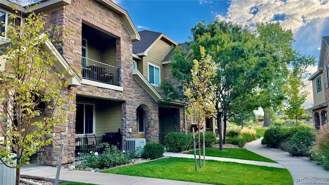 15362 W 66th Ave Unit D, Arvada, CO 80007 - craftsman-style house featuring stone siding, a front yard, a balcony, covered porch, and central AC unit