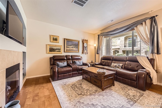 15362 W 66th Ave Unit D, Arvada, CO 80007 - living room featuring a tile fireplace, light wood-style flooring, and baseboards