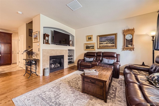 15362 W 66th Ave Unit D, Arvada, CO 80007 - living area featuring light wood-style floors, a tiled fireplace, built in shelves, and baseboards