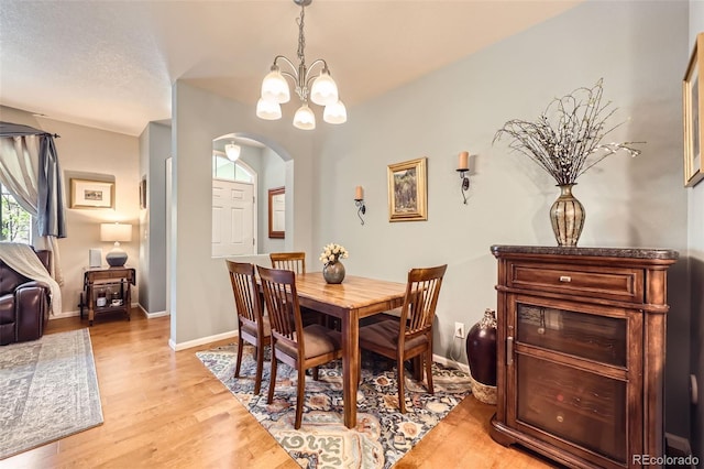 15362 W 66th Ave Unit D, Arvada, CO 80007 - dining area with arched walkways, a chandelier, light wood finished floors, and baseboards