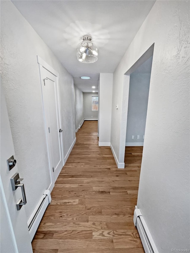 corridor featuring baseboard heating and light hardwood / wood-style floors