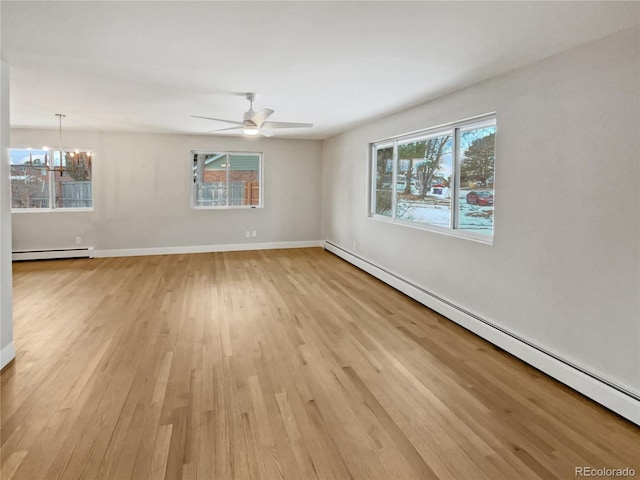 unfurnished room with a baseboard heating unit, ceiling fan with notable chandelier, and light hardwood / wood-style flooring