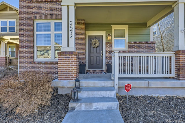 entrance to property featuring covered porch and brick siding