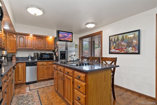 11485 Pecos St, Denver, CO 80234 - kitchen with black appliances, a breakfast bar, brown cabinetry, and a kitchen island