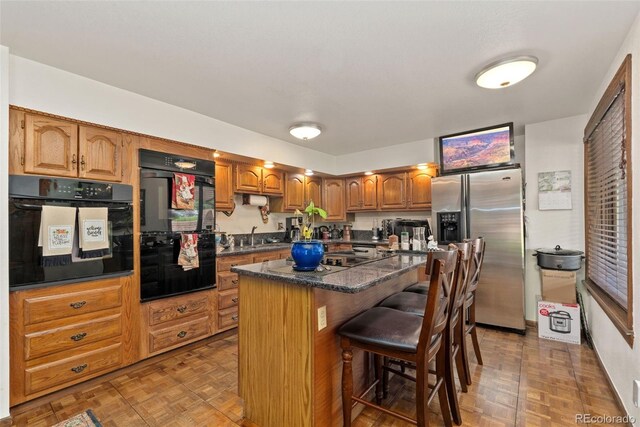 11485 Pecos St, Denver, CO 80234 - kitchen with black appliances, a kitchen island, a kitchen breakfast bar, and brown cabinets