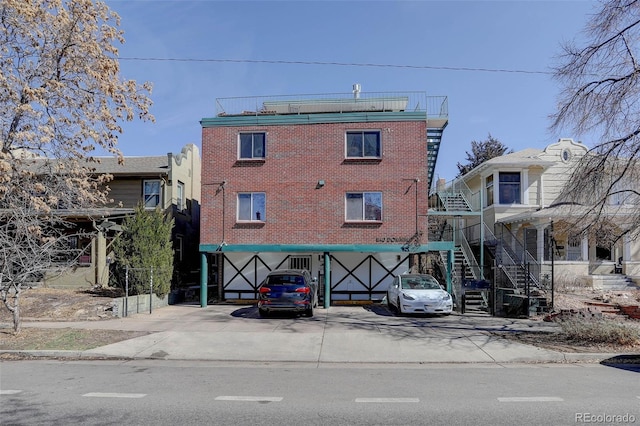 view of building exterior with a garage, stairs, and concrete driveway