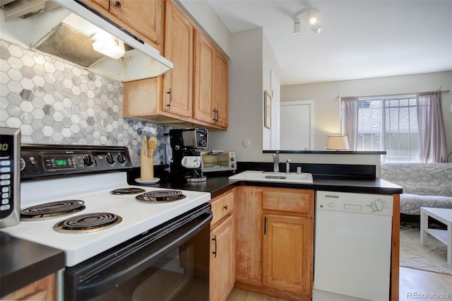 kitchen featuring a peninsula, white dishwasher, under cabinet range hood, a sink, and range with electric stovetop