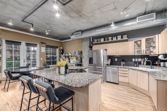 1499 Blake St Unit 4F, Denver, CO 80202 - kitchen featuring light brown cabinets, stainless steel appliances, a sink, light stone counters, and a breakfast bar