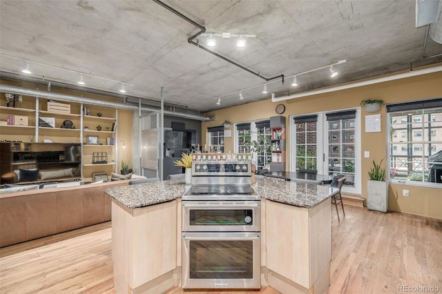 1499 Blake St Unit 4F, Denver, CO 80202 - kitchen featuring double oven range, light wood-style flooring, a kitchen island, and light stone counters