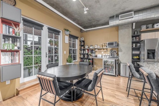 1499 Blake St Unit 4F, Denver, CO 80202 - dining area featuring beverage cooler, light wood finished floors, and rail lighting