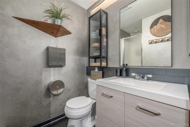 1499 Blake St Unit 4F, Denver, CO 80202 - full bathroom with vanity, toilet, a shower with shower door, and backsplash