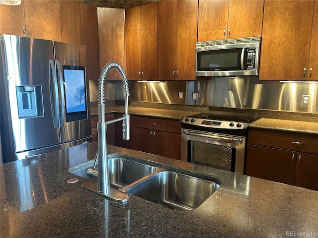 kitchen featuring dark stone countertops, sink, and appliances with stainless steel finishes