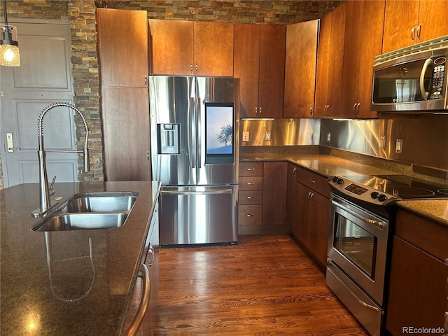 kitchen featuring stainless steel appliances, dark hardwood / wood-style floors, sink, and dark stone countertops