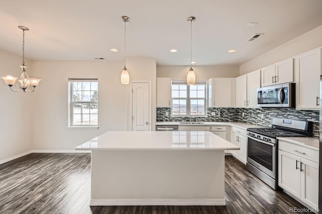 kitchen featuring appliances with stainless steel finishes, plenty of natural light, a kitchen island, and a sink