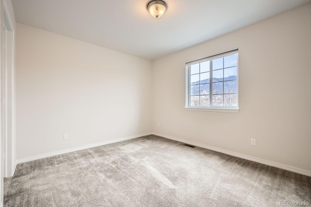 carpeted spare room with visible vents and baseboards