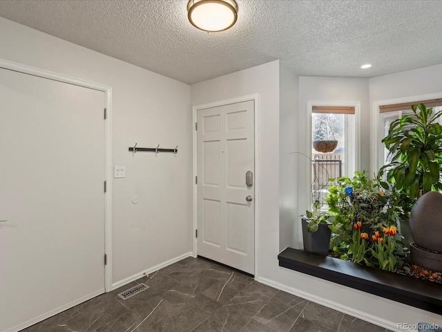 entrance foyer featuring visible vents, a textured ceiling, and baseboards