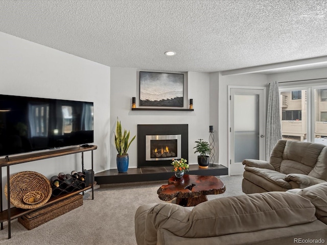 living area featuring recessed lighting, a warm lit fireplace, carpet flooring, and a textured ceiling