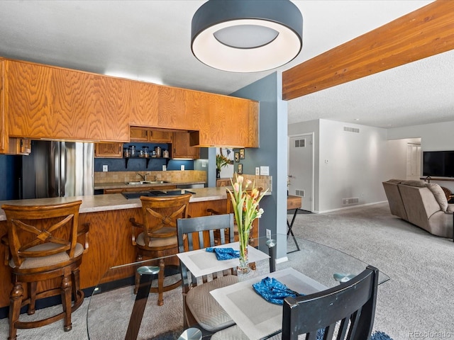 kitchen with freestanding refrigerator, visible vents, light countertops, and a peninsula