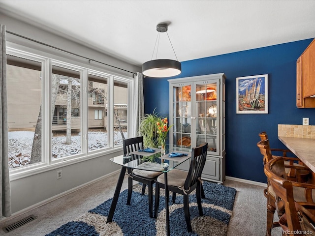 dining area featuring baseboards, visible vents, and light colored carpet