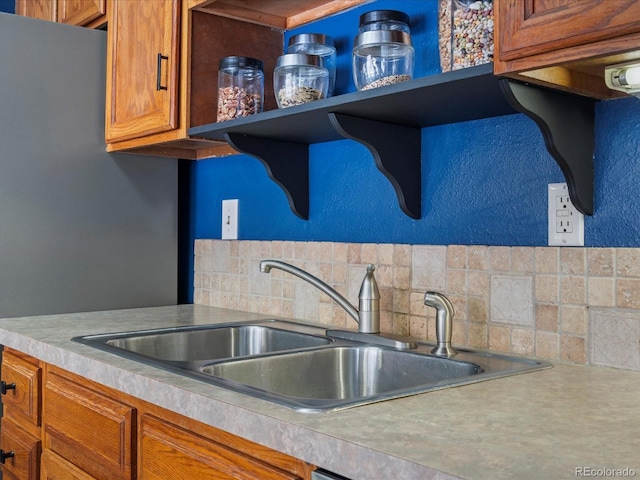 kitchen with open shelves, brown cabinets, a sink, and light countertops