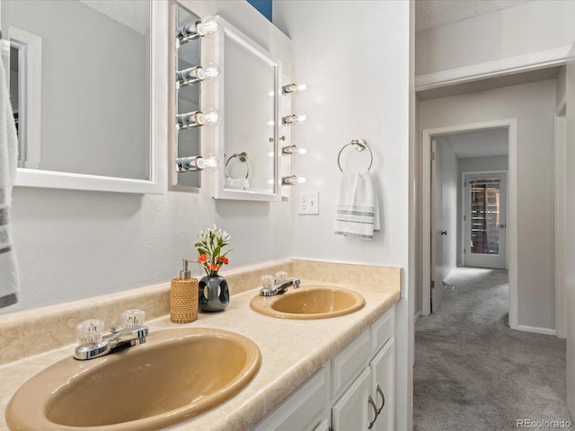 bathroom featuring a sink, a textured ceiling, baseboards, and double vanity