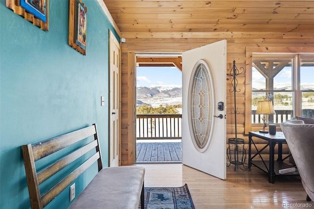 doorway to outside with wooden walls, wooden ceiling, a mountain view, and hardwood / wood-style flooring