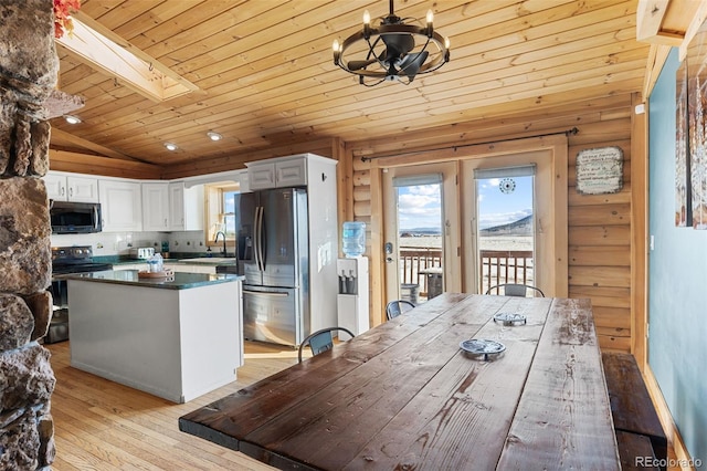 kitchen featuring white cabinets, appliances with stainless steel finishes, lofted ceiling with skylight, wood ceiling, and light hardwood / wood-style flooring