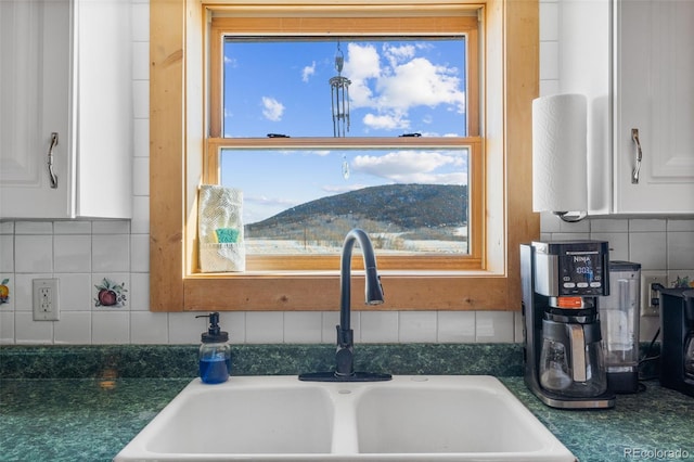 room details with sink, backsplash, white cabinetry, and a mountain view