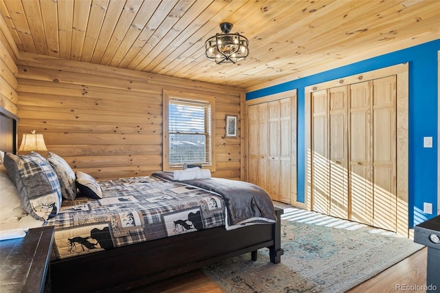 bedroom with hardwood / wood-style flooring, two closets, and wood ceiling