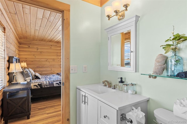 bathroom with hardwood / wood-style flooring, wooden ceiling, toilet, and vanity