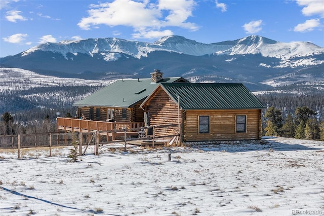 snow covered house with a deck with mountain view