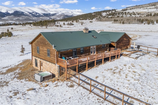 snow covered rear of property featuring a deck with mountain view and central AC