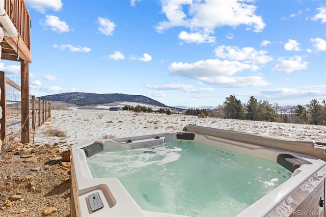 snow covered pool featuring a mountain view and a hot tub