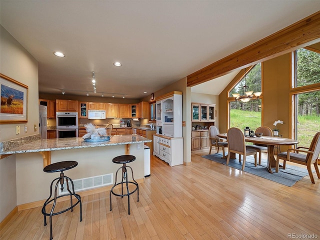 13094 Molly Dr, Conifer, CO 80433 - kitchen with stainless steel appliances, light stone countertops, light wood-style flooring, a breakfast bar, and recessed lighting