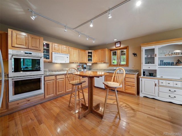13094 Molly Dr, Conifer, CO 80433 - kitchen featuring white appliances, rail lighting, glass insert cabinets, and light wood finished floors
