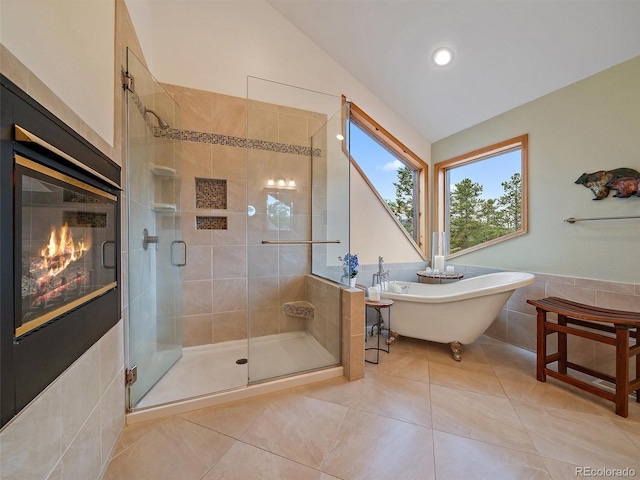 13094 Molly Dr, Conifer, CO 80433 - bathroom featuring vaulted ceiling, a stall shower, a glass covered fireplace, a freestanding bath, and tile patterned floors