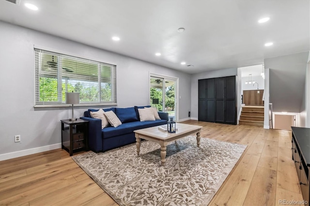 living room featuring light wood-style floors, baseboards, stairs, and recessed lighting