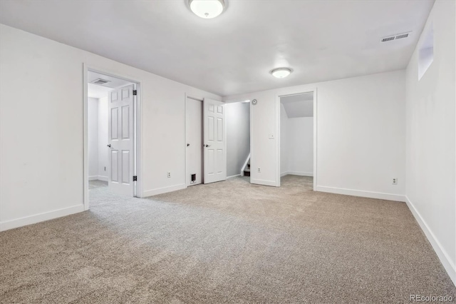 unfurnished bedroom featuring light carpet, baseboards, and two closets