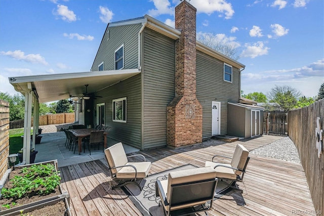 wooden deck featuring a ceiling fan, outdoor dining area, and a fenced backyard