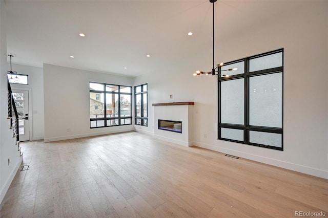 unfurnished living room with light hardwood / wood-style flooring and a notable chandelier