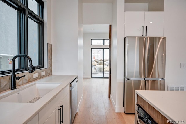 kitchen featuring white cabinetry, appliances with stainless steel finishes, sink, and light wood-type flooring