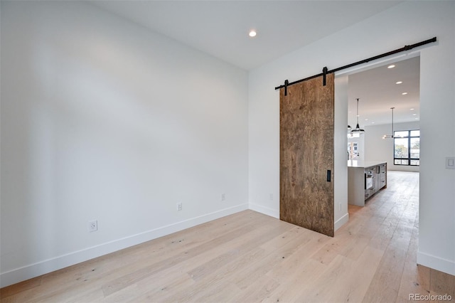 spare room with light hardwood / wood-style floors and a barn door