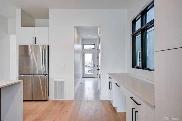 kitchen featuring white cabinetry, light hardwood / wood-style floors, and stainless steel fridge